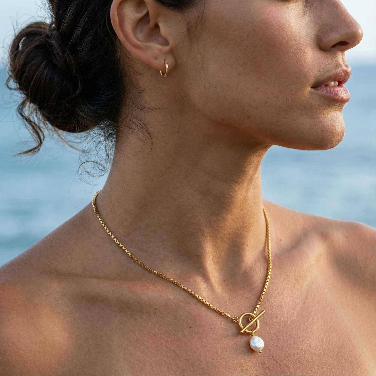 Woman wearing La Isla Pearl Toggle Necklace by Brother & Sisters, featuring a gold clasp and freshwater pearl.