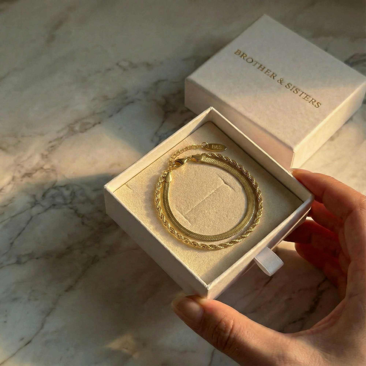 Ios Layered Bracelet in a gift box by Brother & Sisters, showcasing gold herringbone and twisted rope textures.