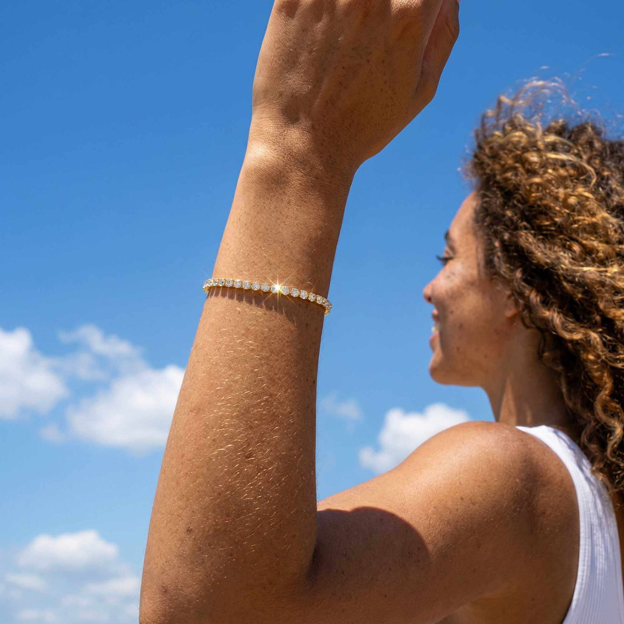 Woman wearing a Tennis Bracelet by Brother & Sisters, enjoying a sunny outdoor day with a glamorous sparkle.