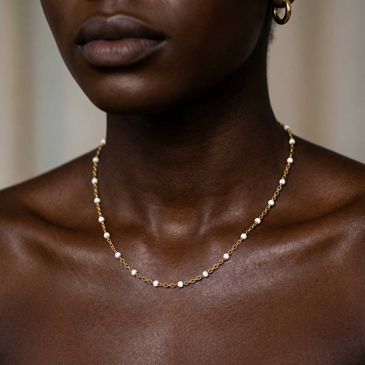 White Beaded Choker by Brother & Sisters, featuring delicate white enamel beads on a gold chain.