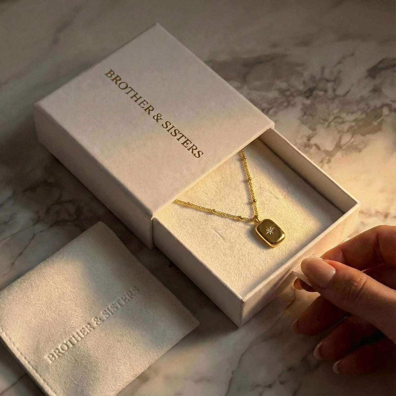 Starlight Pendant Necklace in a gift box by Brother & Sisters, showcasing polished gold tag with starburst and zirconia.