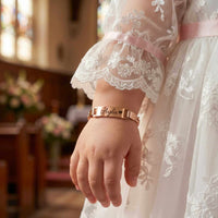 Thumbnail for Infant Bracelet by Brother & Sisters featuring a personalized name, worn by a baby in a beautiful dress.