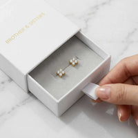Thumbnail for Crystal Flower Stud Earrings in a white box by Brother & Sisters, showcasing delicate four-leaf design and sparkle.