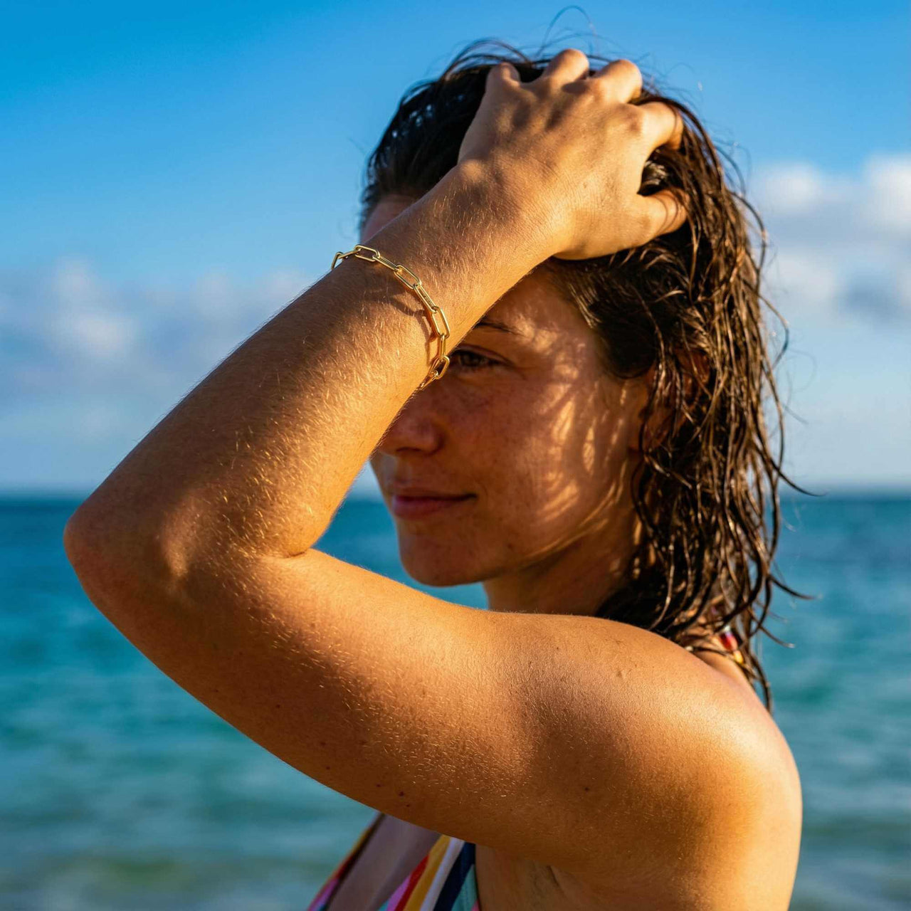 Woman wearing Paperclip Chain Bracelet by Brother & Sisters on a sunny beach, showcasing its minimalist style.