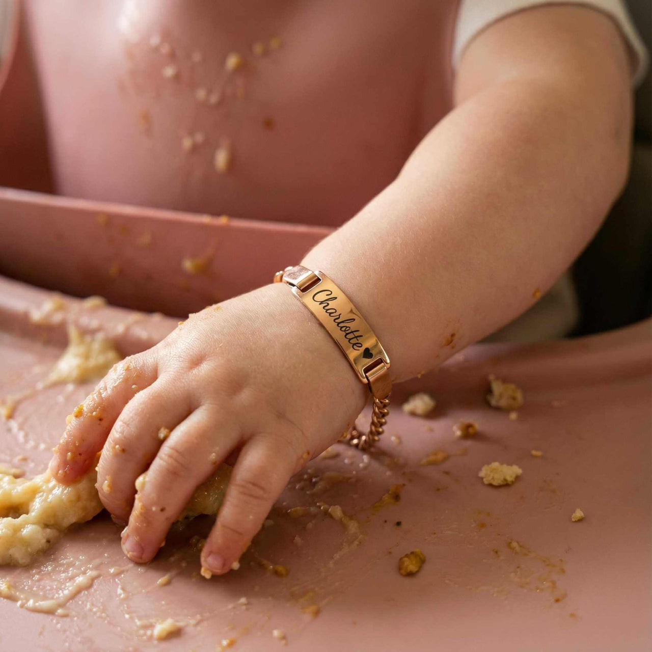 Infant Bracelet on baby's wrist during mealtime, personalized with name Charlotte, by Brother & Sisters.