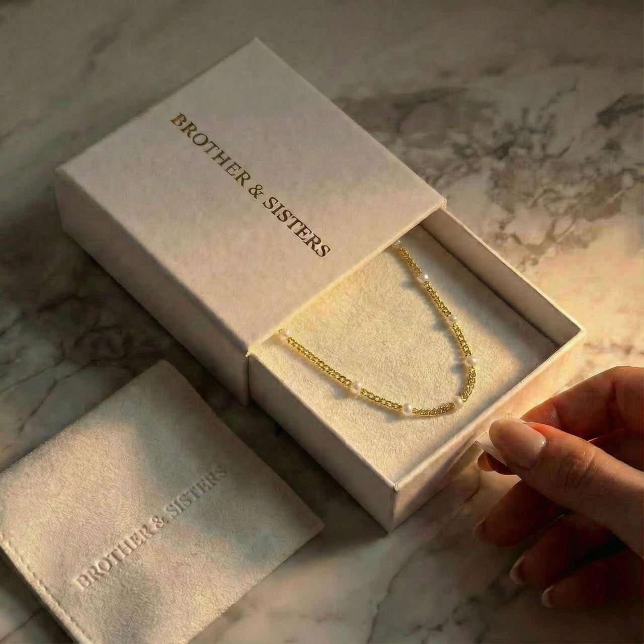 Dainty Pearl Choker displayed in BROTHER & SISTERS packaging, featuring tiny freshwater pearls on a gold chain.