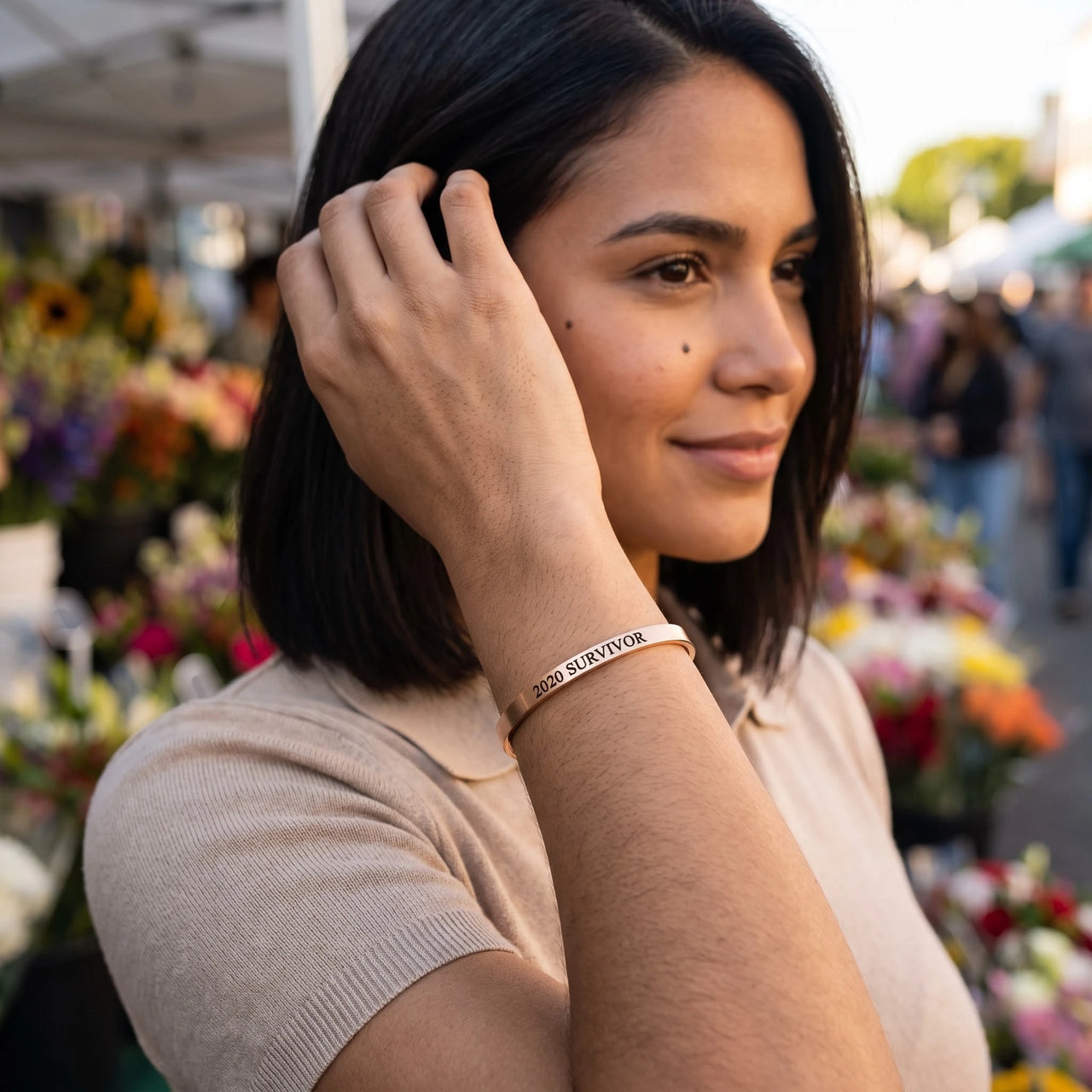 Woman gently touching her 2020 Survivor bracelet in rose gold | SKU: 2020s-rg