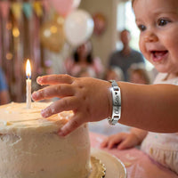 Thumbnail for Infant Bracelet with personalized name on a child's wrist, celebrating a birthday with a cake.