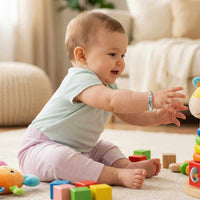 Thumbnail for Infant Bracelet on baby playing with colorful toys, showcasing personalized charm by Brother & Sisters.