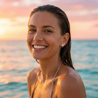 Thumbnail for Smiling woman wearing Crystal Flower Stud Earrings by Brother & Sisters by the ocean at sunset.