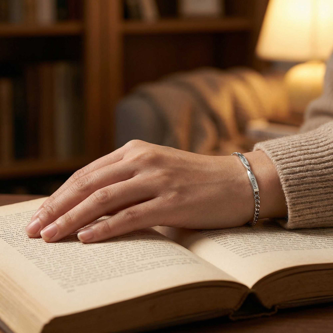 Infinity Bond Matching Bracelet on a hand resting on an open book, showcasing love and connection by Brother & Sisters.