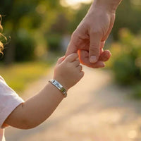 Thumbnail for Infant Bracelet personalized with a child's name, held by an adult hand, from Brother & Sisters.