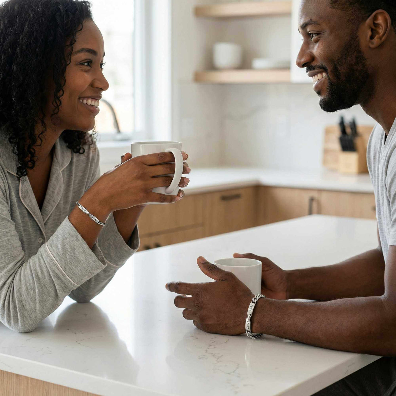 Couple sharing a moment in the kitchen wearing Infinity Bond Matching Bracelets by Brother & Sisters.
