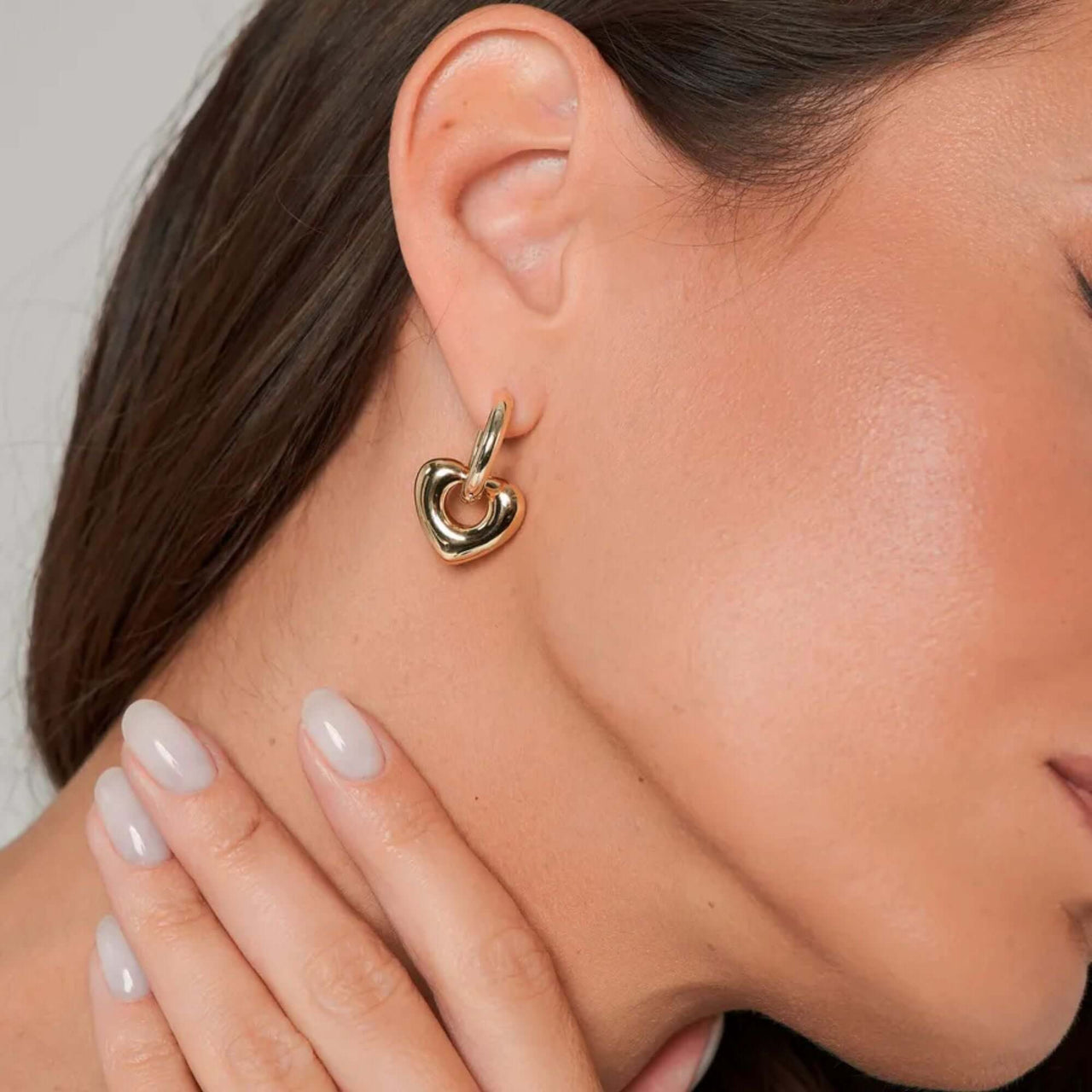 Aurora Heart Hoops gold earrings by Brother & Sisters worn by a woman, showcasing elegance and style.