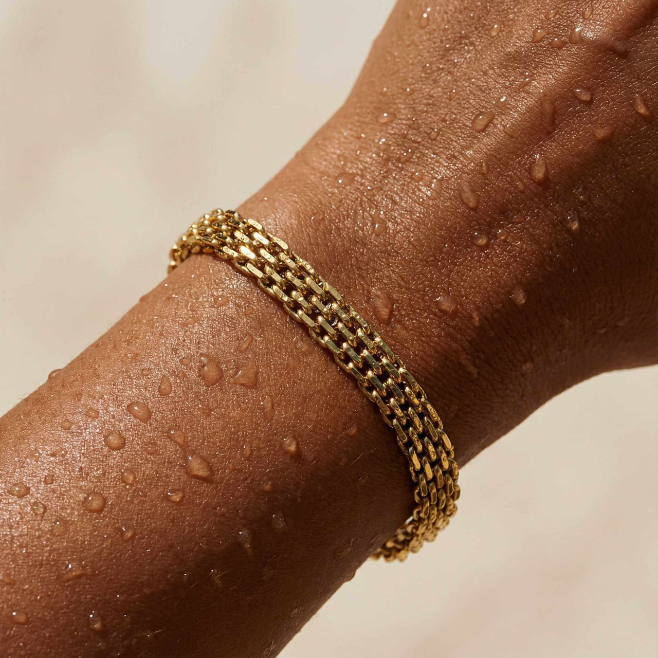 Sifnos Woven Bracelet on a hand with water droplets, showcasing its premium gold mesh design from Brother & Sisters.