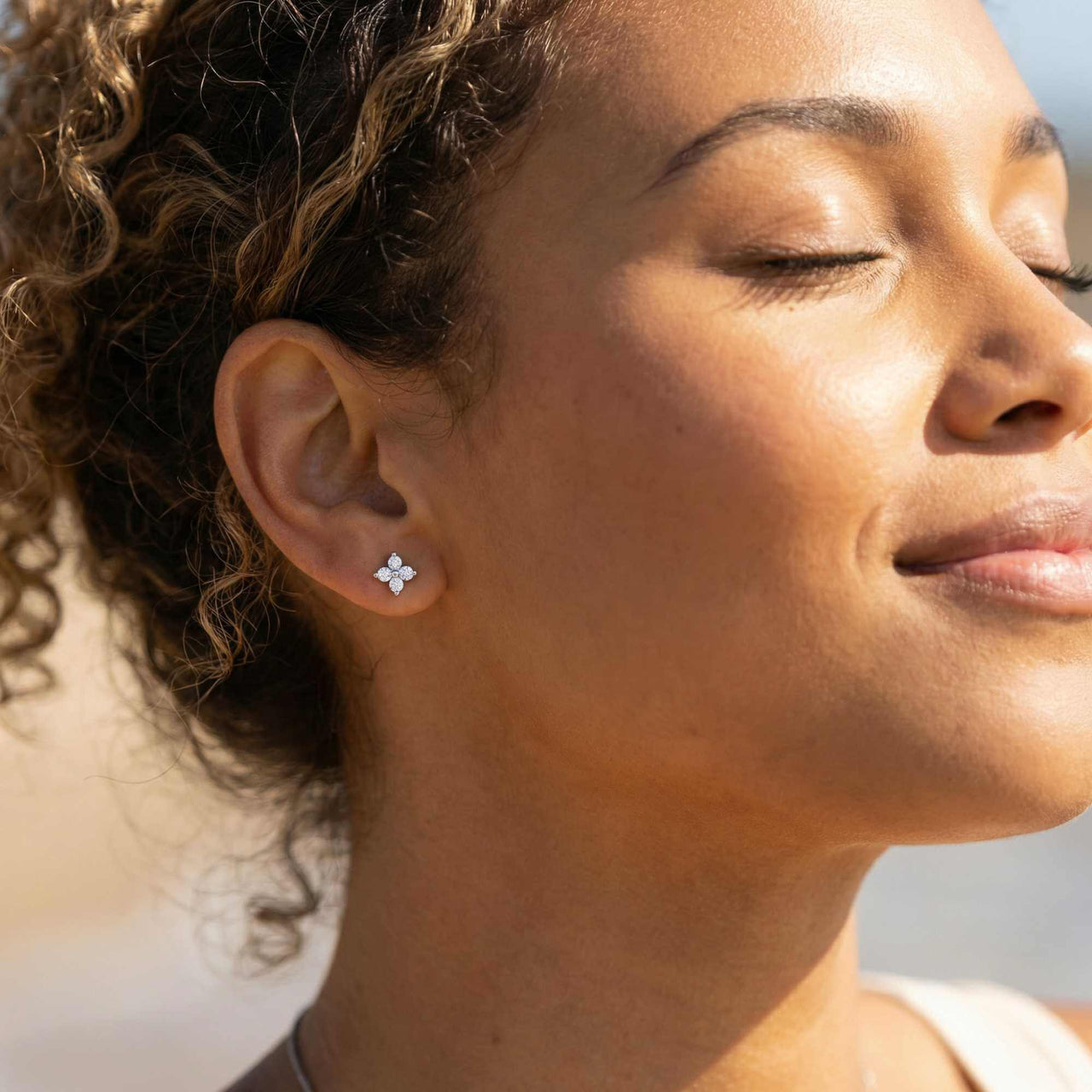 Woman wearing Crystal Flower Stud Earrings, showcasing the tiny four-leaf design and elegant sparkle by Brother & Sisters.