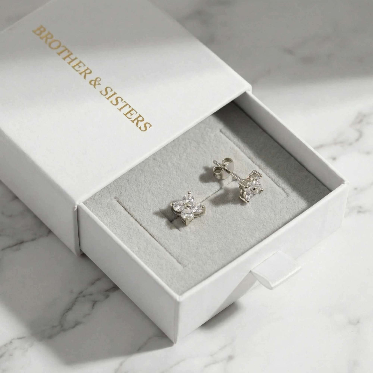 Crystal Flower Stud Earrings in a branded Brother & Sisters box, showcasing tiny four-leaf zirconia designs.