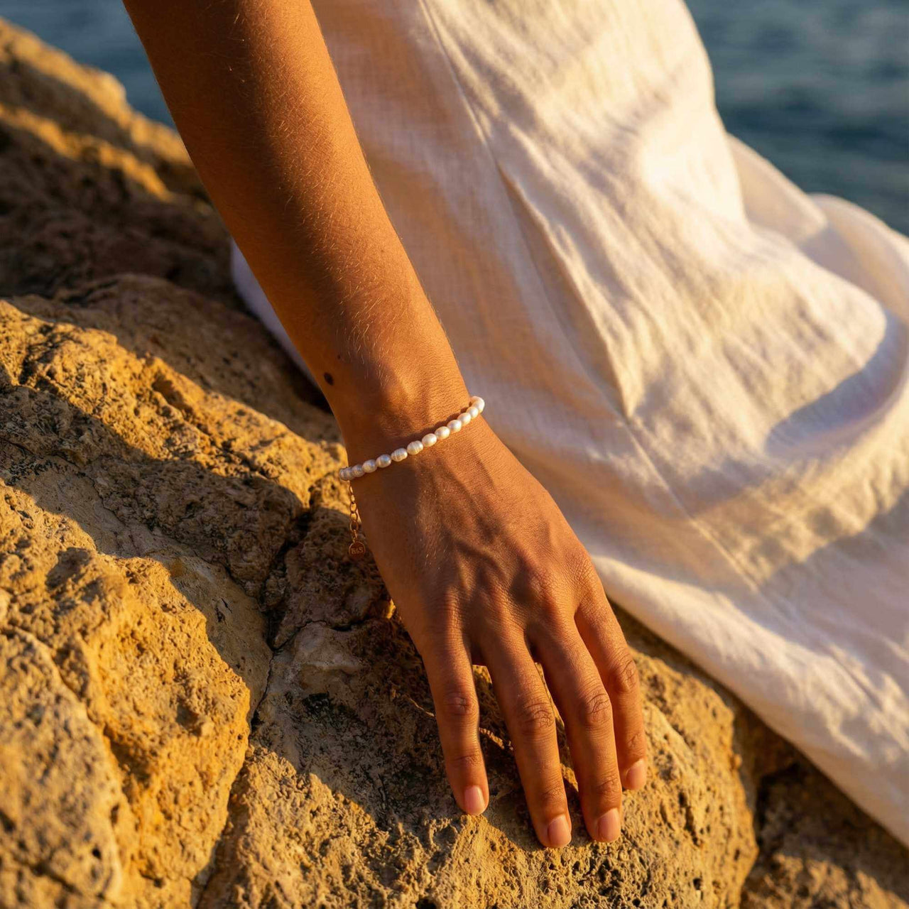 Freshwater Pearl Bracelet worn on a hand resting on rocks, handcrafted by Brother & Sisters, showcasing unique pearls.