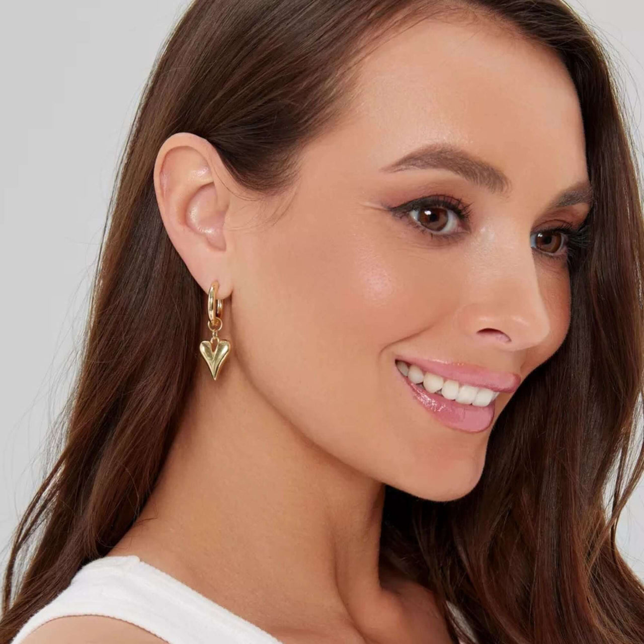 Amora Heart Drops gold earrings worn by a model showcasing their romantic and bold design by Brother & Sisters.