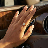 Thumbnail for Crystal Flower Ring worn on a hand resting on a luxury car steering wheel, showcasing its delicate design and sparkle.