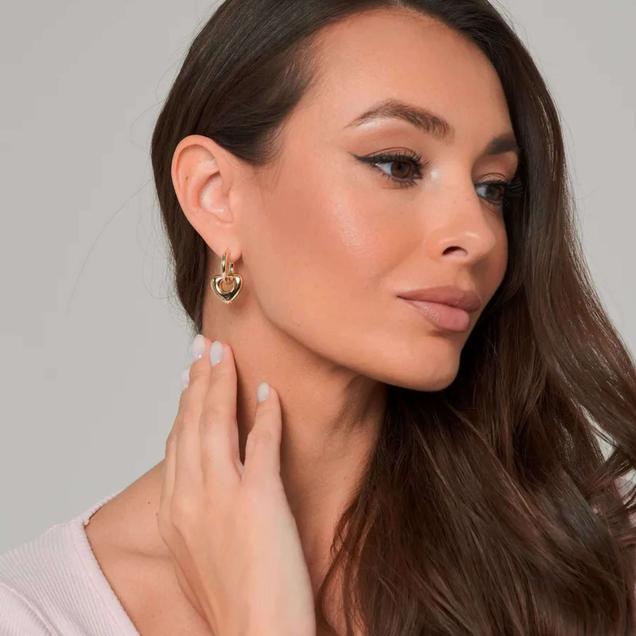 Woman wearing Aurora Heart Hoops gold earrings by Brother & Sisters, showcasing elegance and femininity.