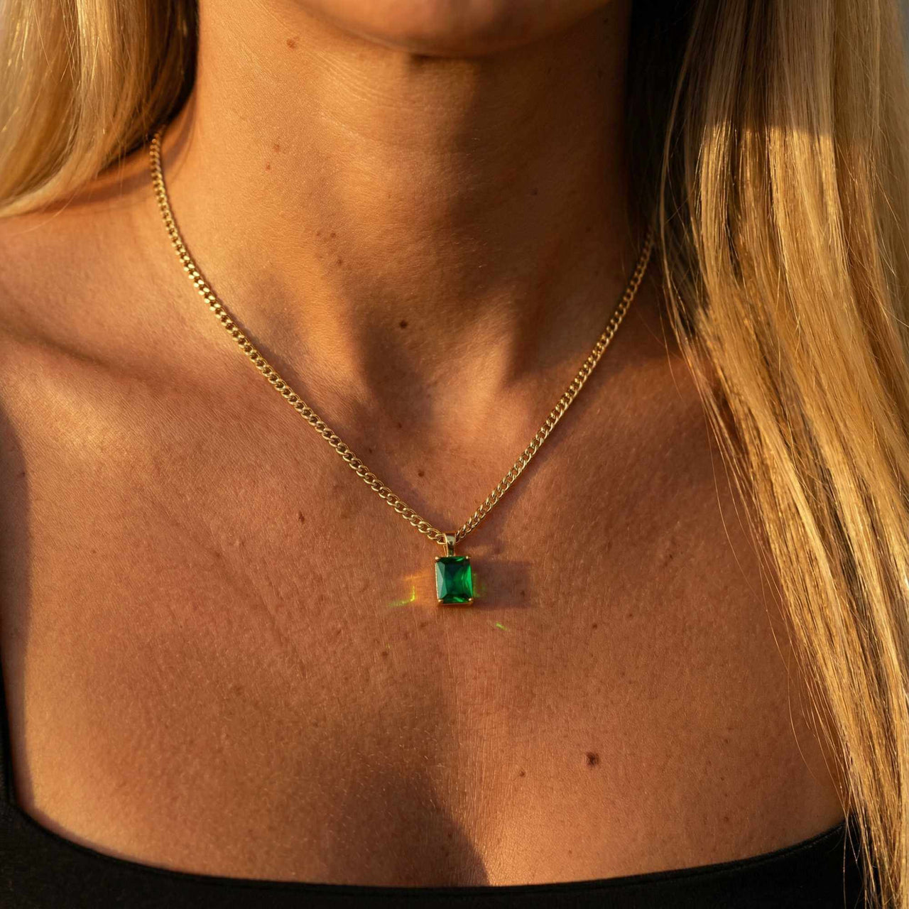 Emerald Pendant Necklace by Brother & Sisters featuring a stunning emerald green stone set in gold.
