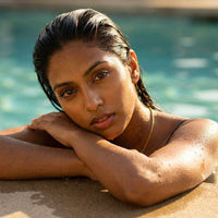 Thumbnail for Woman relaxing by the pool wearing a delicate necklace, showcasing effortless beauty and natural glow.