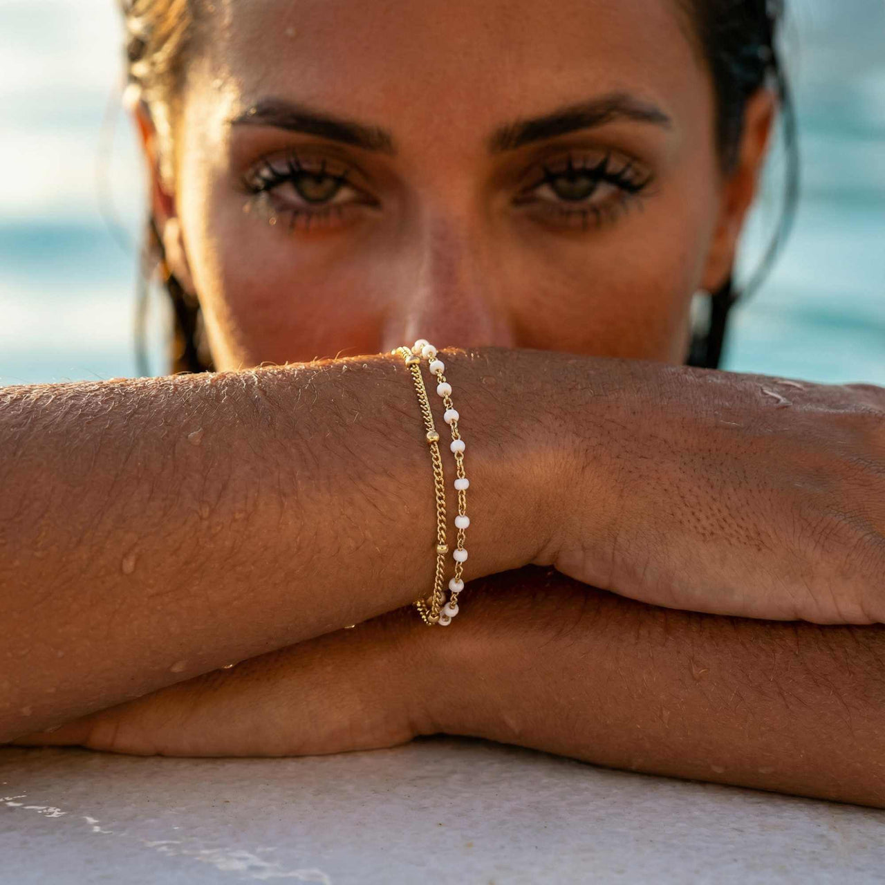 Model showcasing the Double White Bracelet with a white enamel beaded chain and gold link by Brother & Sisters.