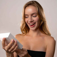 Thumbnail for Excited woman opening a gift box, showcasing the joy of receiving a Love Photo Necklace from Brother & Sisters.