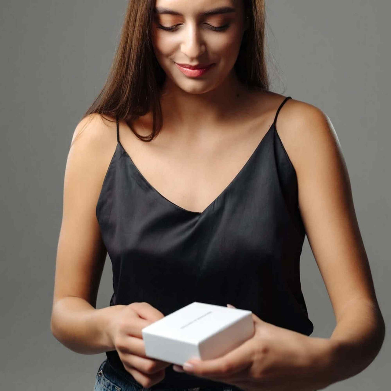 Woman unboxing a Sunflower Photo Necklace gift box by Brother & Sisters, wearing a stylish black top.