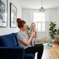 Thumbnail for Mother happily holding her baby in a cozy living room with play mat, showcasing bonding moments.