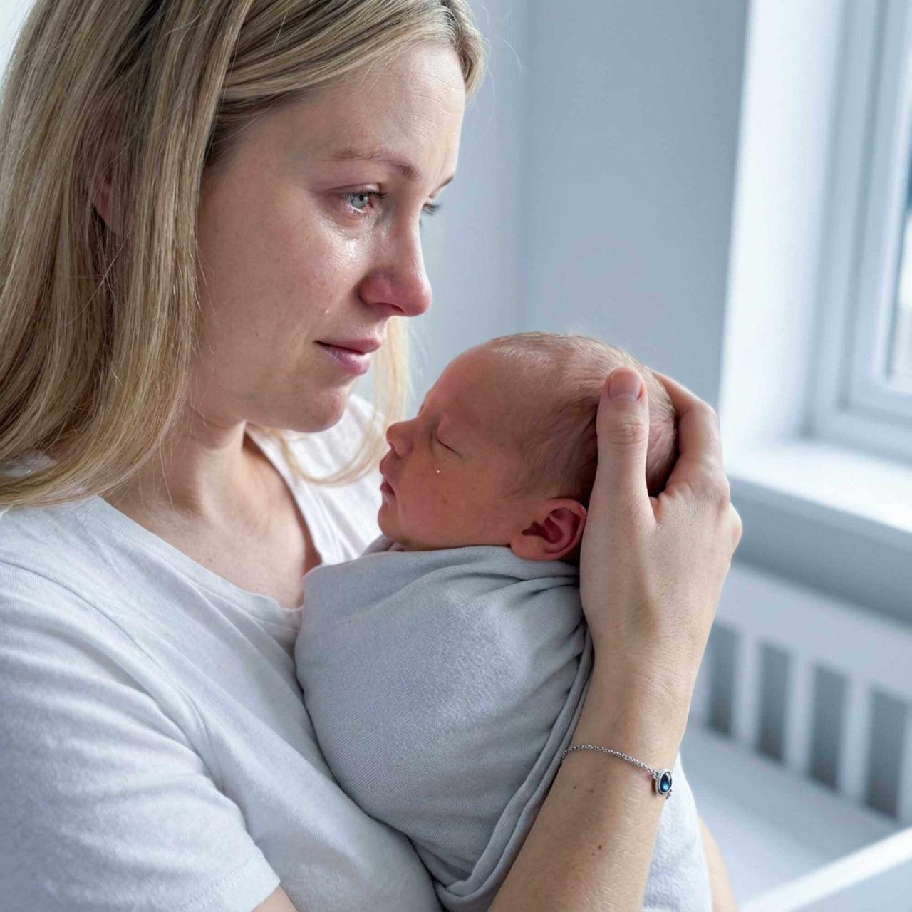 A mother holding her newborn baby, wearing a Photo Projection Bracelet by Brother & Sisters, capturing precious memories.