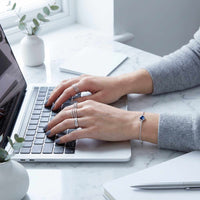 Thumbnail for Photo Projection Bracelet by Brother & Sisters, featured on a woman’s wrist while typing on a laptop.