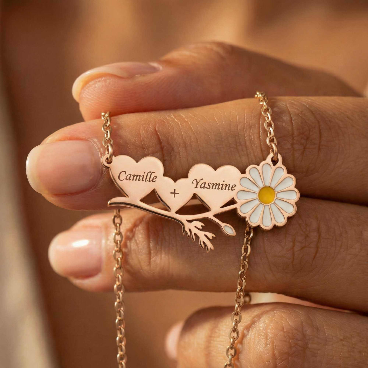 Daisy Name Necklace showing connected hearts with names Camille and Yasmine, featuring a white enamel daisy, by Brother & Sisters.