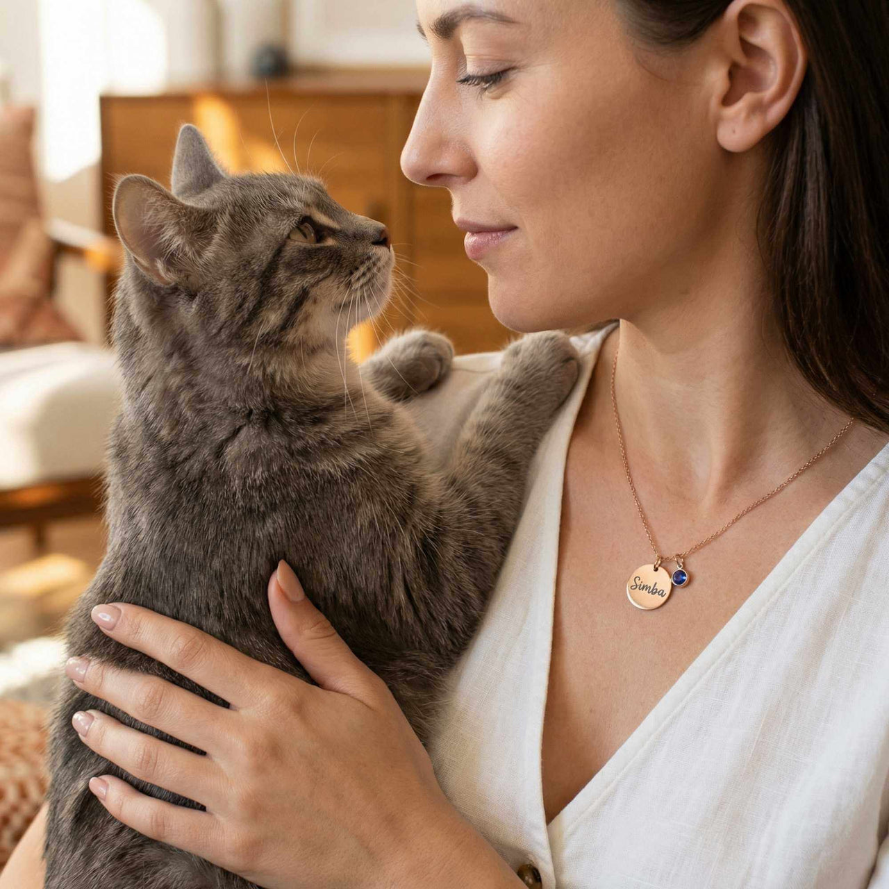 Precious Name Necklace worn by a woman with a cat, featuring an engraved name and birthstone crystal by Brother & Sisters.
