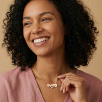 Thumbnail for Daisy Name Necklace worn by a smiling woman, featuring engraved names in hearts and a white enamel daisy.