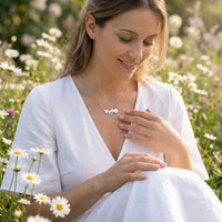 Thumbnail for Daisy Name Necklace worn by a woman in a field of daisies, featuring engraved names and a white enamel daisy, by Brother & Sisters.