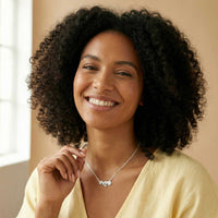 Thumbnail for Daisy Name Necklace worn by a smiling woman, showcasing the delicate design with three connected hearts by Brother & Sisters.