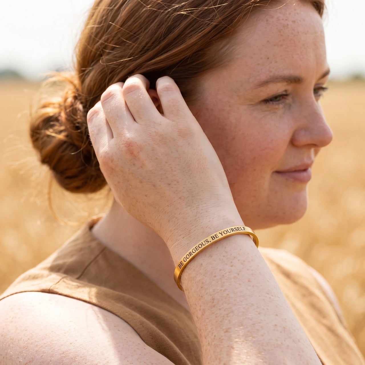 Woman gently touching her Be Gorgeous, Be Yourself bracelet in gold | SKU: bgby-g