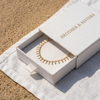 Thumbnail for Sun Ray Fringe Anklet in a Brother & Sisters box on sandy background, showcasing delicate gold design and summer vibes.