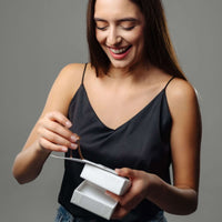 Thumbnail for A woman joyfully unboxing the Classic Name Necklace from Brother & Sisters, showcasing its personalized design.