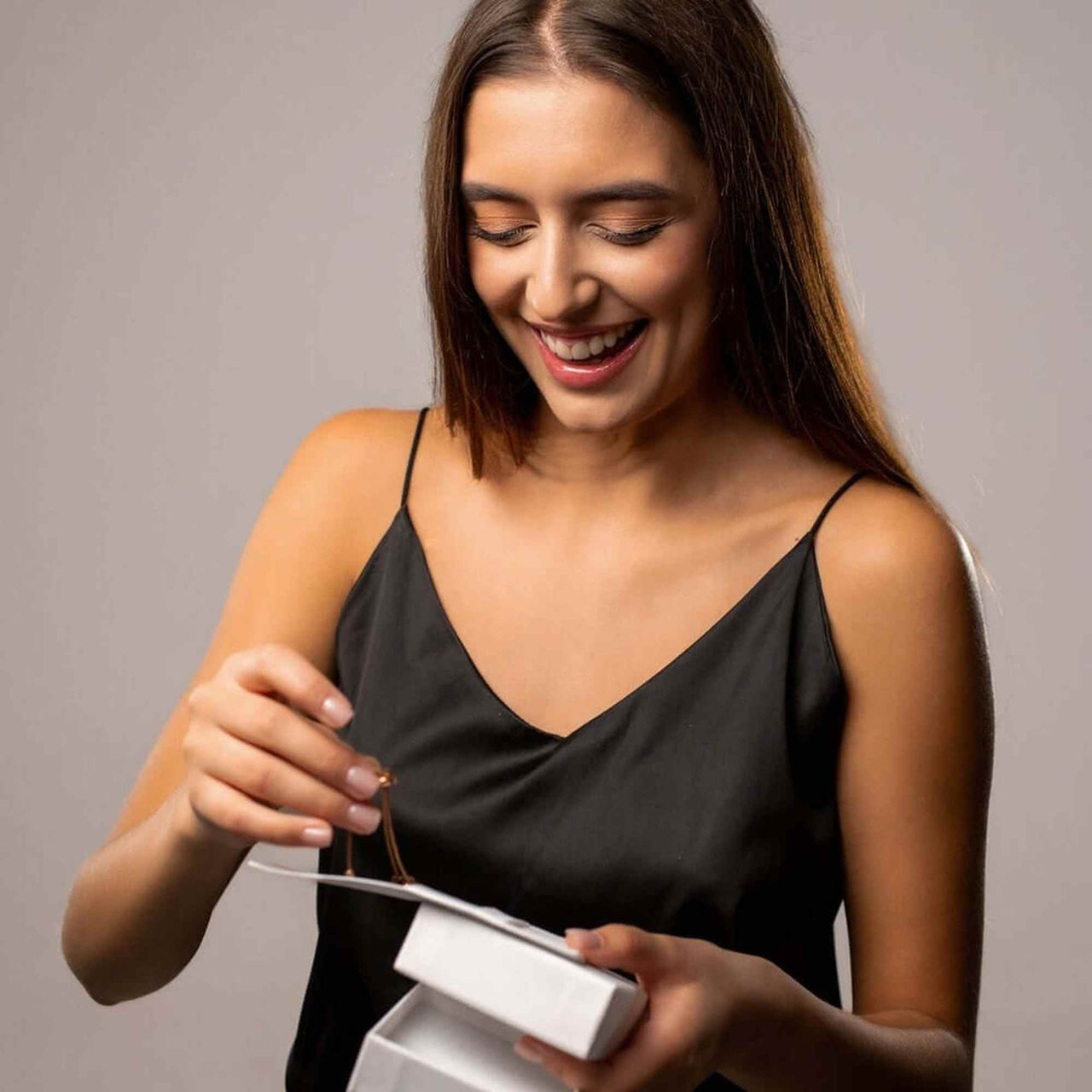 Happy woman unboxing the Timeless Photo Necklace gift from Brother & Sisters, showcasing its elegance and charm.