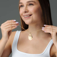 Thumbnail for Woman showcasing the Drop Name Necklace, a personalized jewelry piece by Brother & Sisters, featuring a drop-shaped design.