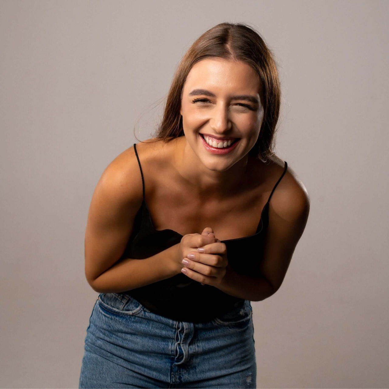 Smiling woman in black top showcasing joy and happiness, perfect for promoting the Drop Photo Necklace by Brother & Sisters.