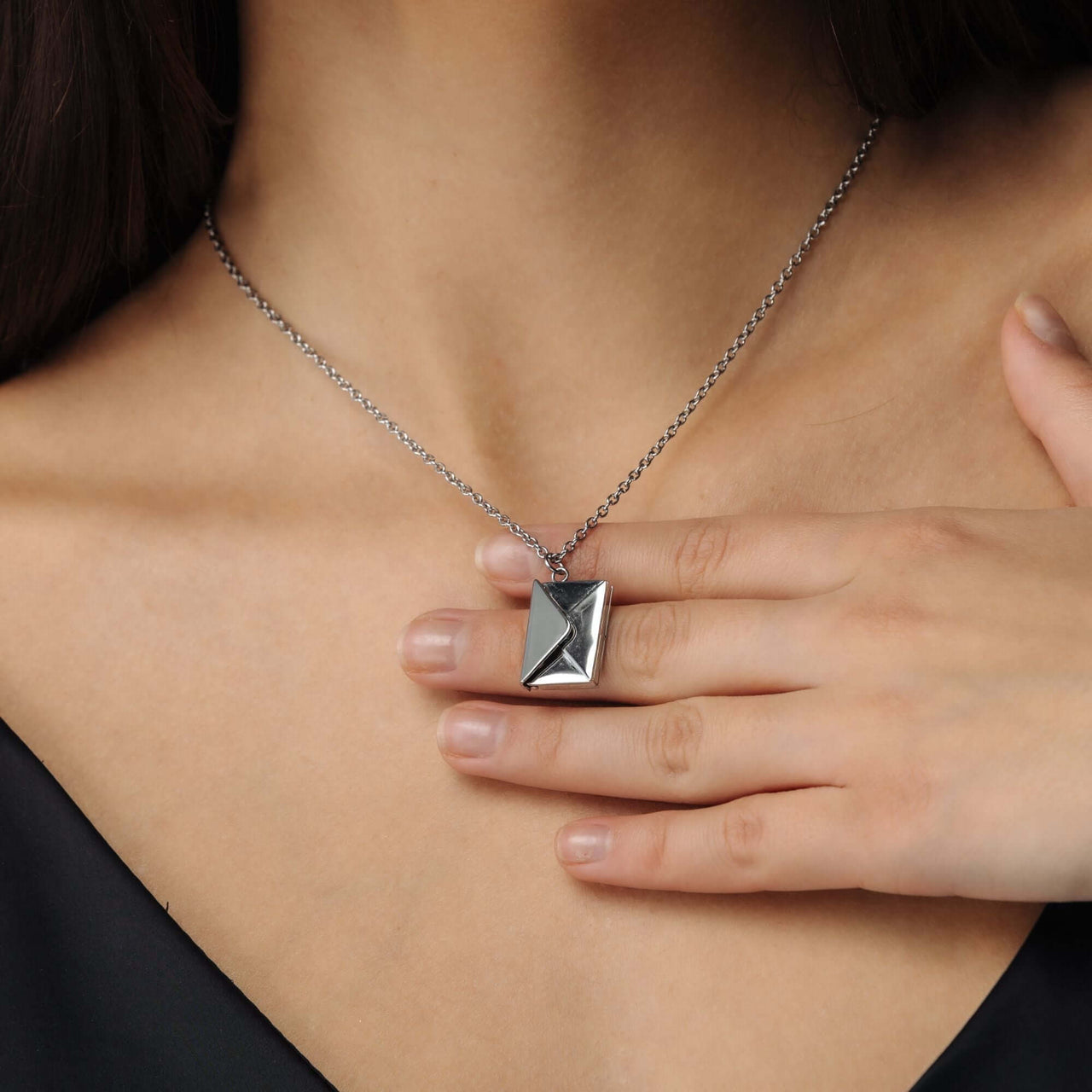 Envelope Name Necklace by Brother & Sisters, featuring an elegant silver design worn on a model's neck.
