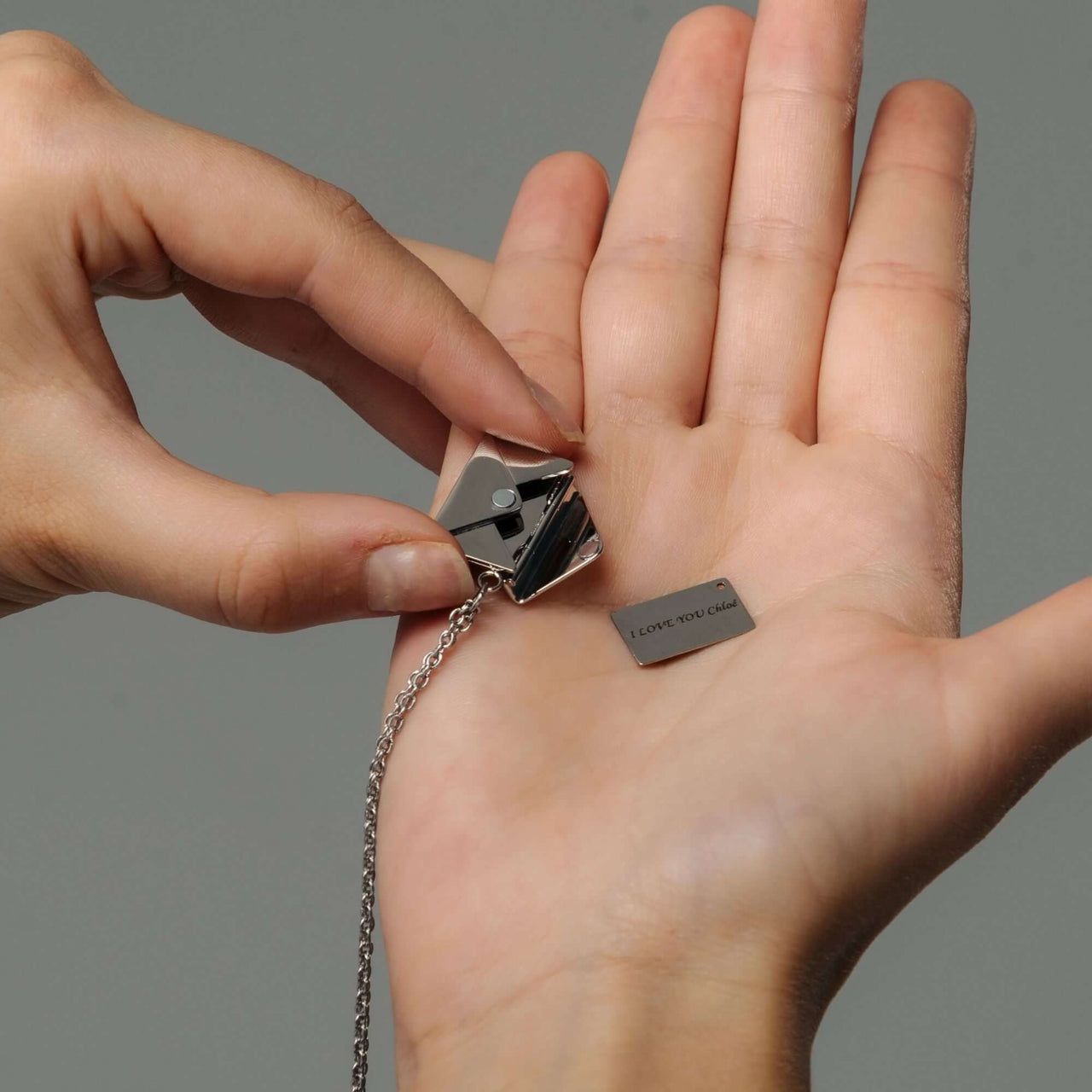 Envelope Name Necklace by Brother & Sisters showcasing a personalized pendant held in a hand.