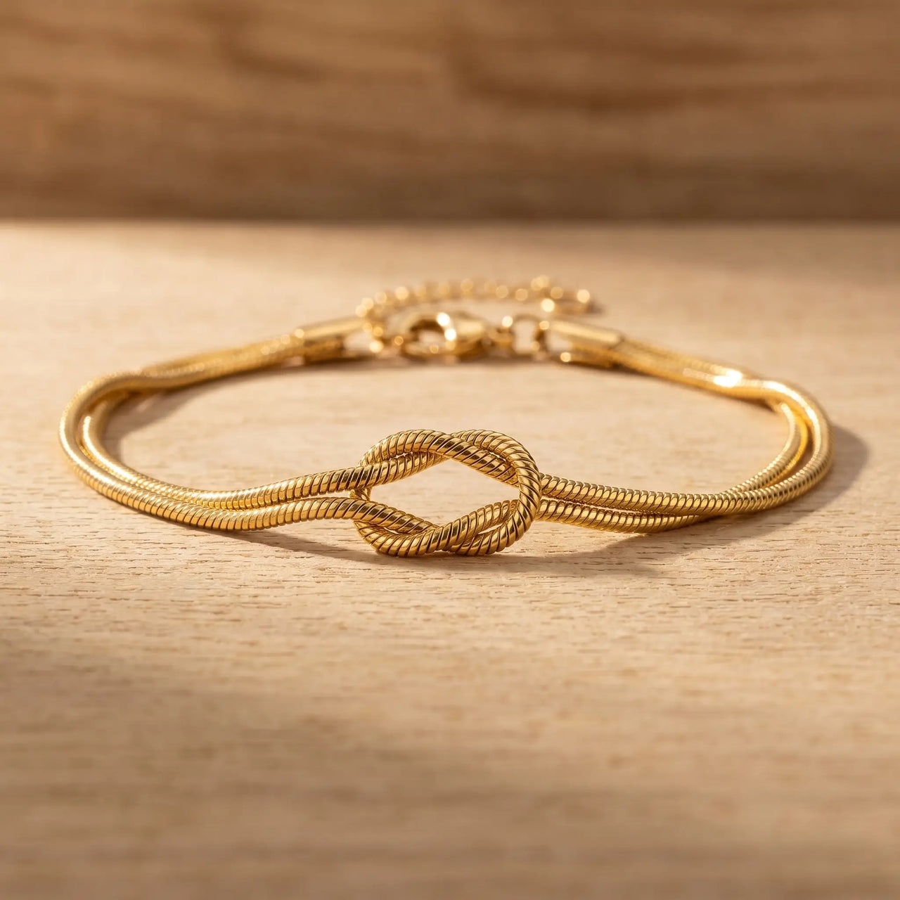 Knot Couple Bracelet gold macro detail flat on wood surface
