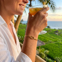 Thumbnail for Knot Couple Bracelet gold worn with cocktail at Bali rice terrace restaurant golden hour