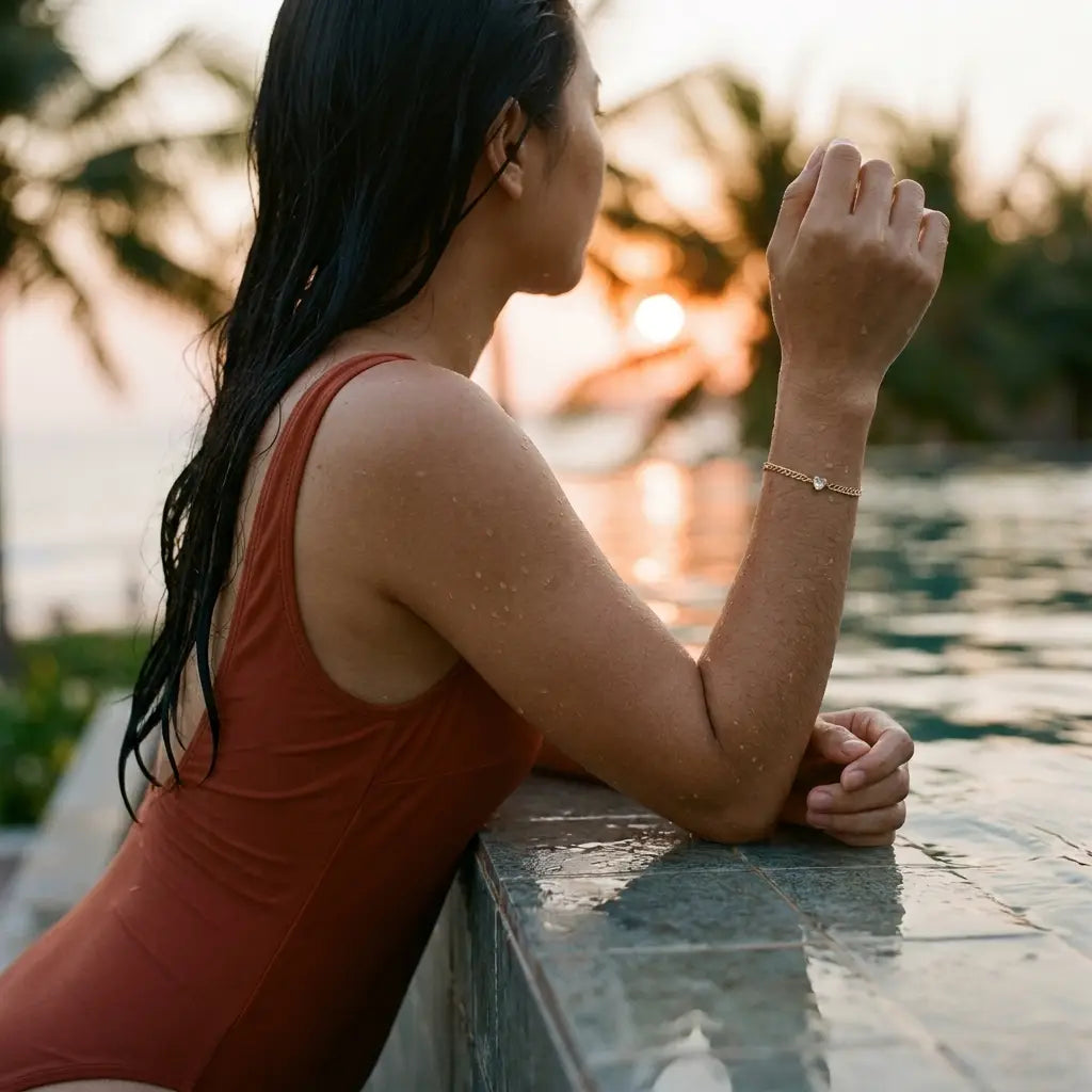 Vietnamese woman at tropical infinity pool wearing gold Heart Bond bracelet