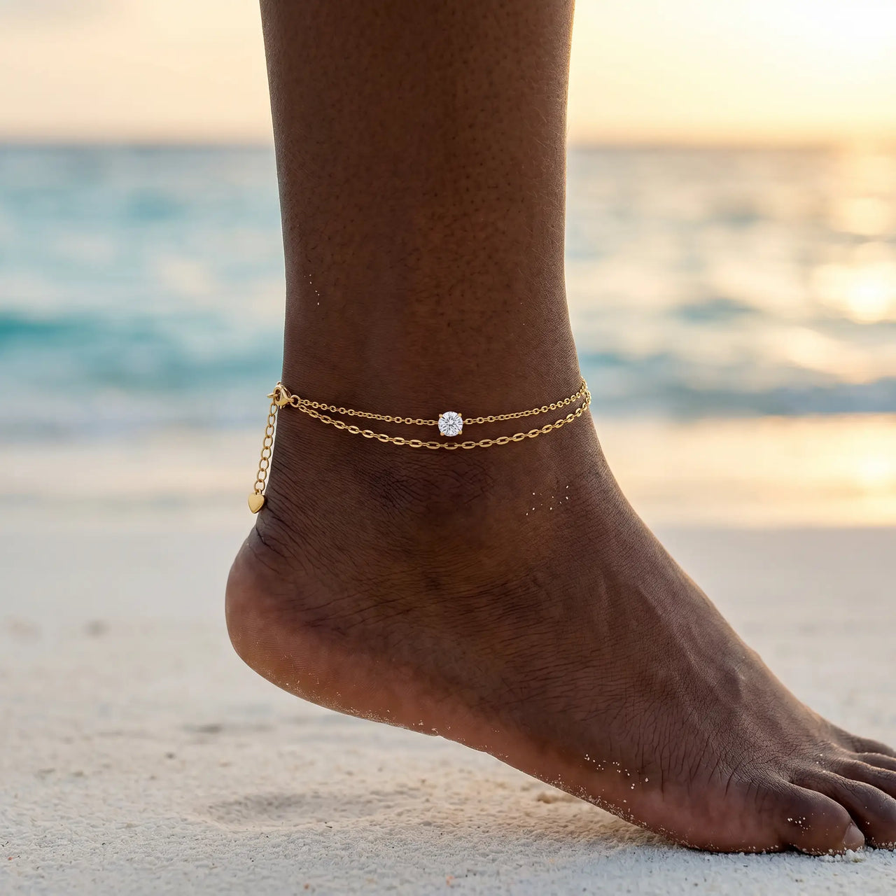 Amalfi Layered Anklet on Caribbean Black model ankle at Maldives sunset — golden hour beach lifestyle, 2 layered gold chains with CZ, waterproof B&S 316L